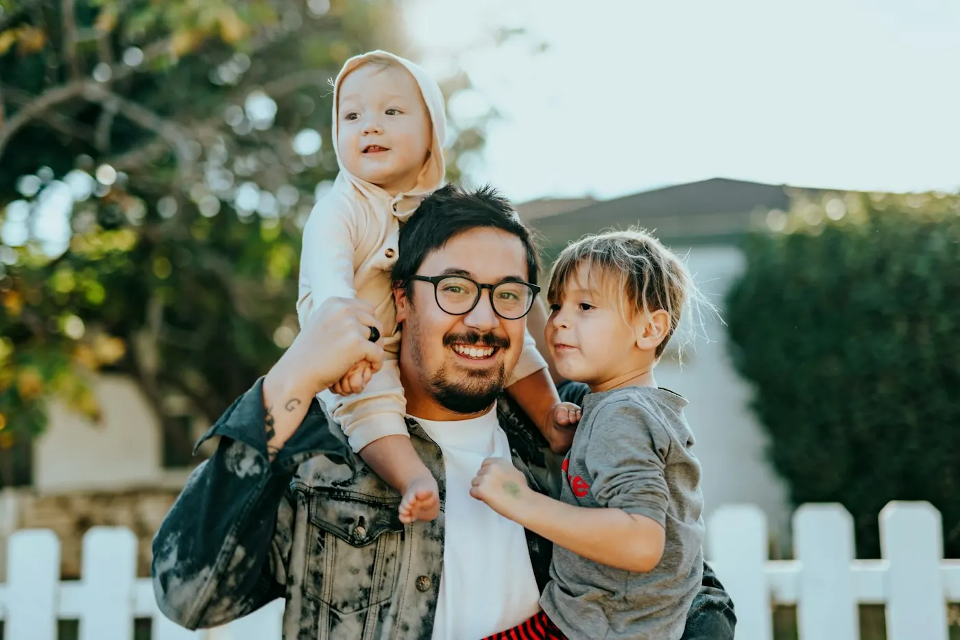A father holding his two young children outdoors