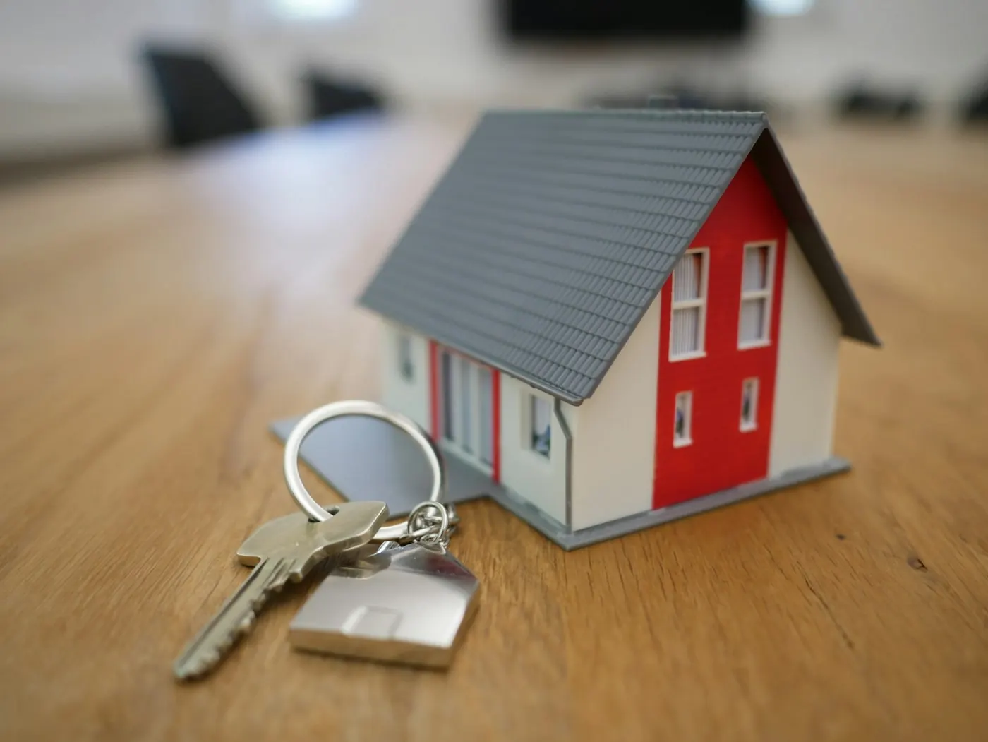 A small house model and keys on a wooden table
